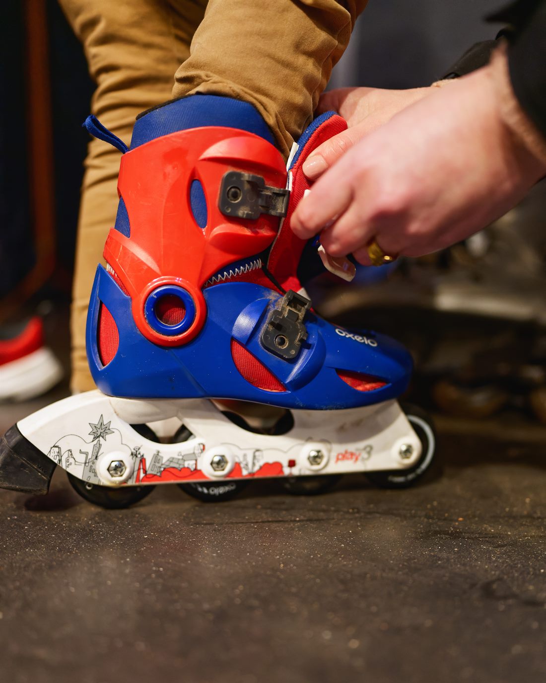 Mains réglant la boucle d’une paire de rollers d’enfant